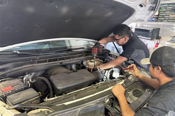 Technicians working under the hood of a vehicle